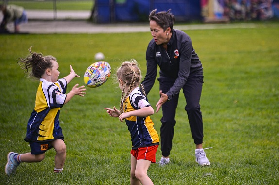 Two young girls playing rugby with Minister Melanie Mark